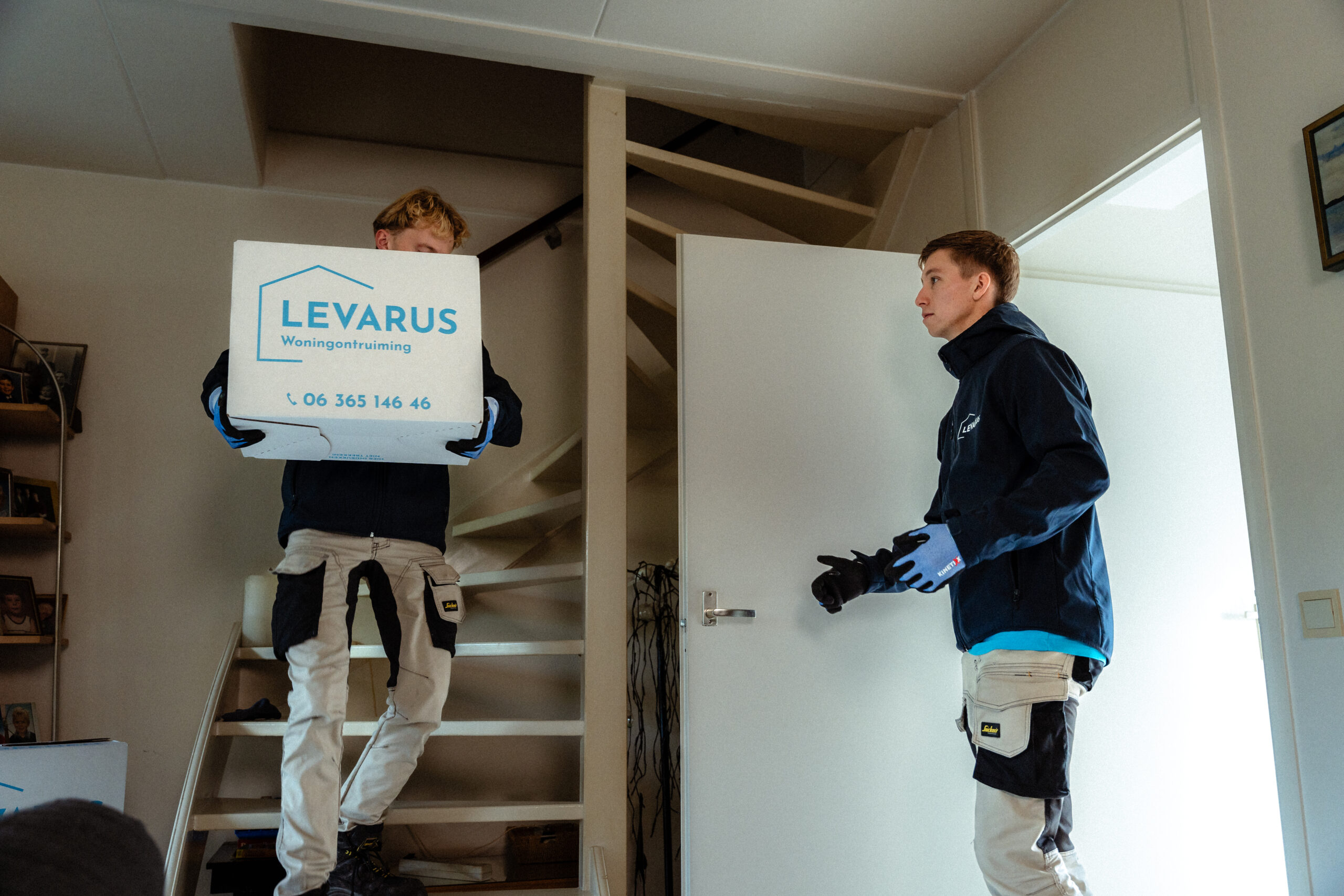 Man komt van de trap om een verhuisdoos over te geven.