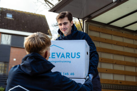 twee mannen geven twee verhuisdozen aan elkaar over.